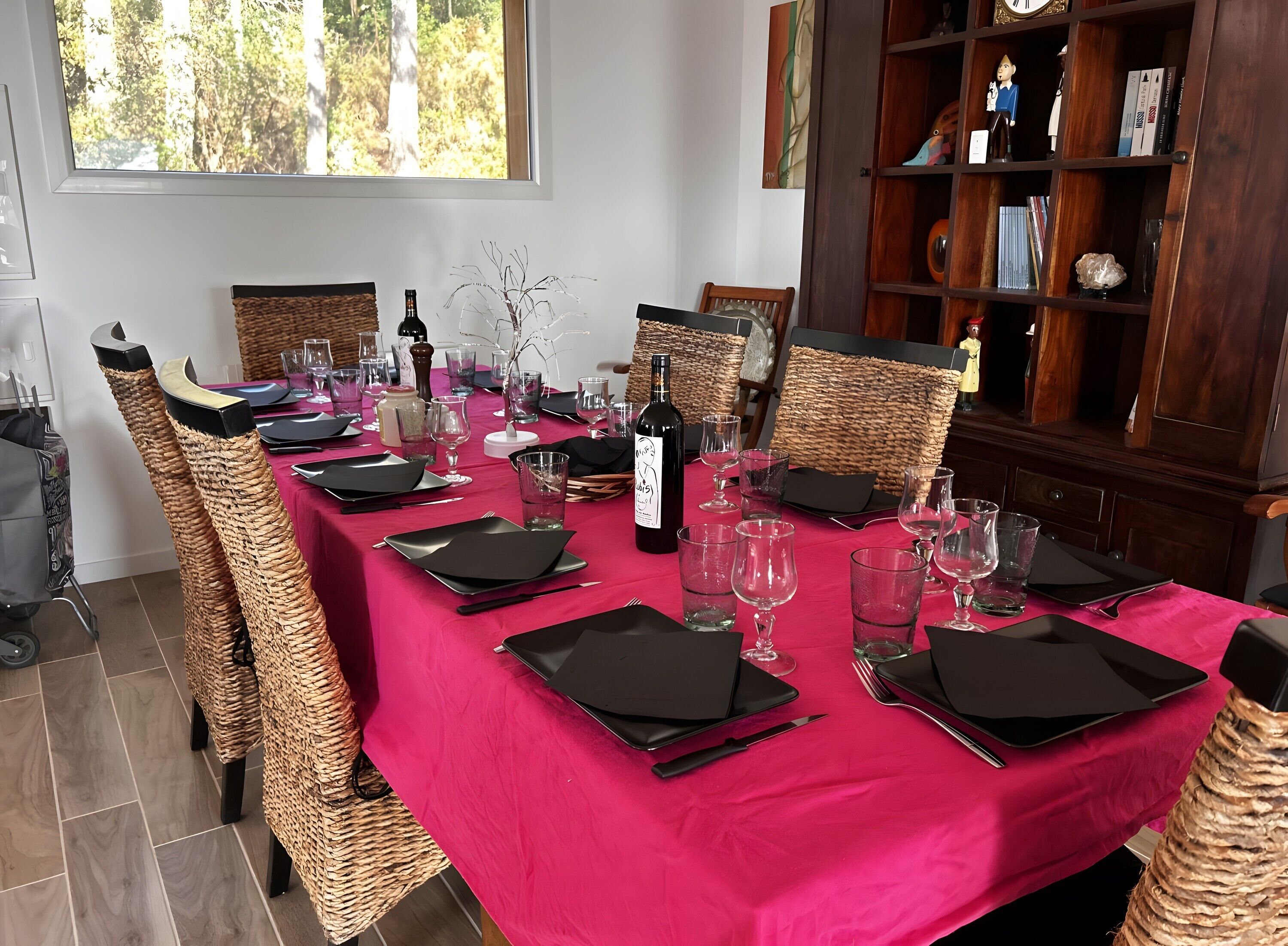 Une table à manger dressée avec des serviettes noires, des verres à vin et une bouteille de vin.