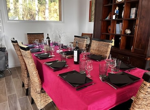 Une table à manger dressée avec des serviettes noires, des verres à vin et une bouteille de vin.