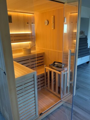 A sauna with wooden slats, a clock, and a control panel. - Oasis Luxury Residences (Zakynthos)