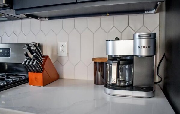 Une cuisine équipée d’une machine à café Keurig, d’un bloc à couteaux et d’une casserole en acier inoxydable.