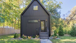A modern, dark-colored building with a triangular roof, a front door, and a small window. - Cozy Cabin On The Esopus Creek in Saugerties, New York (Saugerties)