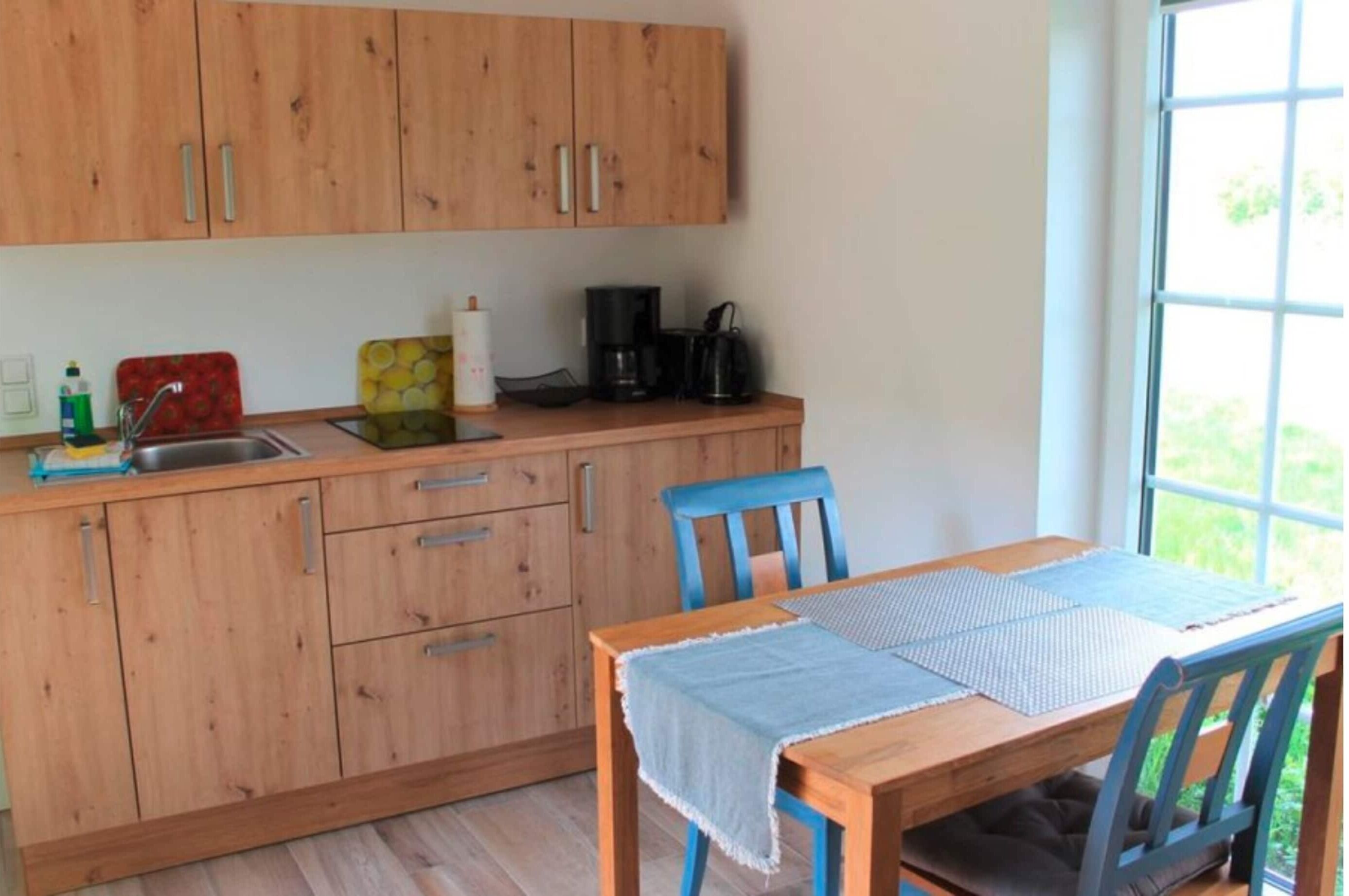 A kitchen with wooden cabinets, a sink, a coffee maker, and a table with a placemat.