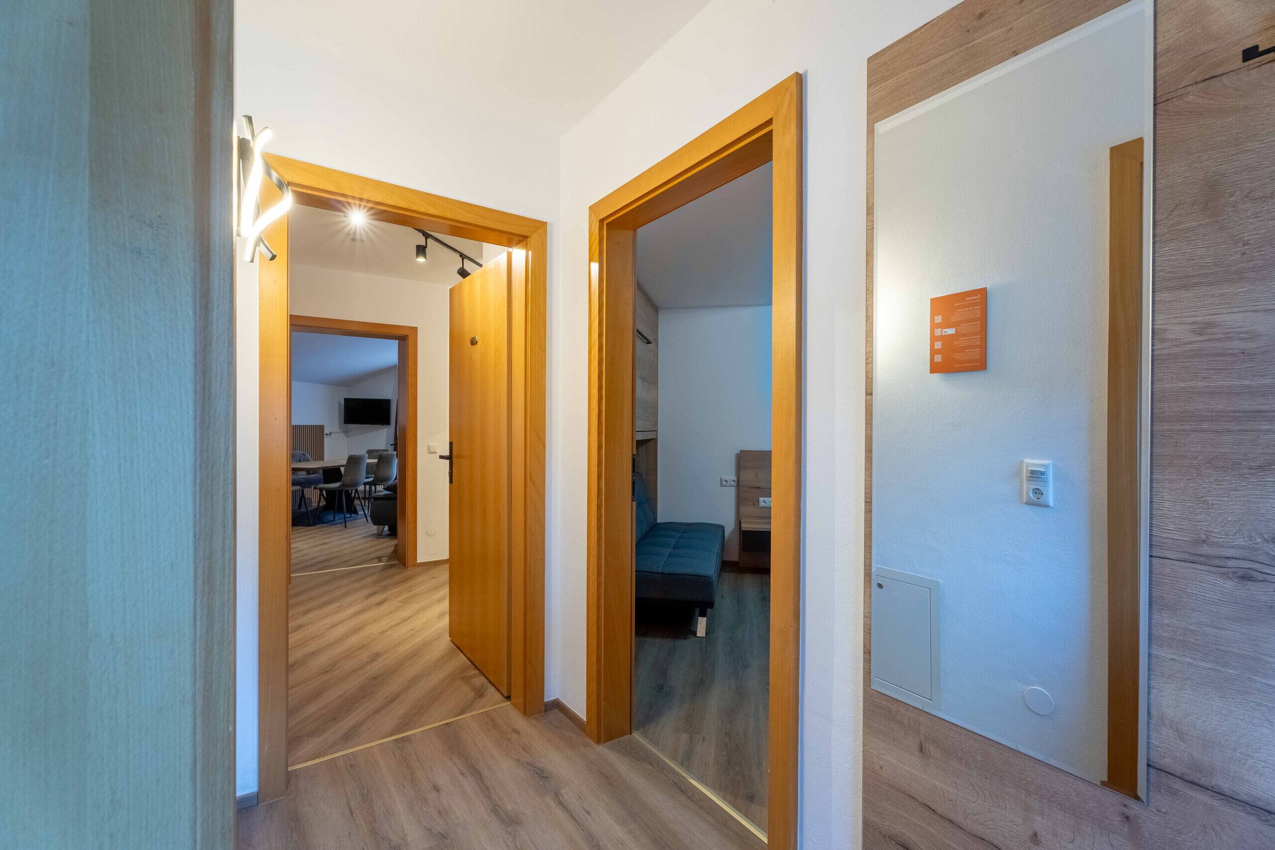 A hallway with wooden flooring and doors leading to different rooms.