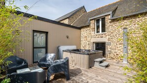 Un bâtiment en pierre doté d’une terrasse en bois, de sièges extérieurs et d’une cheminée en pierre.