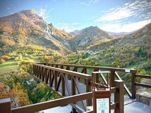 A scenic view from a bridge overlooking a valley with autumn foliage, a sign encouraging visitors to take selfies, and a QR code for more information. - Casa Peña Prieta - V.R. El Canton (Cucayo)