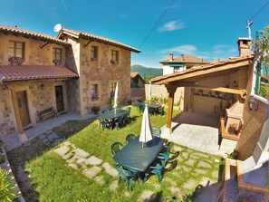 Un patio con edificios de piedra, mobiliario exterior y una pérgola.