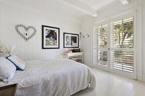 A bedroom with a bed, a dresser, a heart-shaped wall decoration, and two framed pictures. - illiac in Somers - absolute beachfront. (Somers)