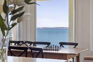 A dining area with a chessboard, a table, and chairs, overlooking a body of water. - illiac in Somers - absolute beachfront. (Somers)
