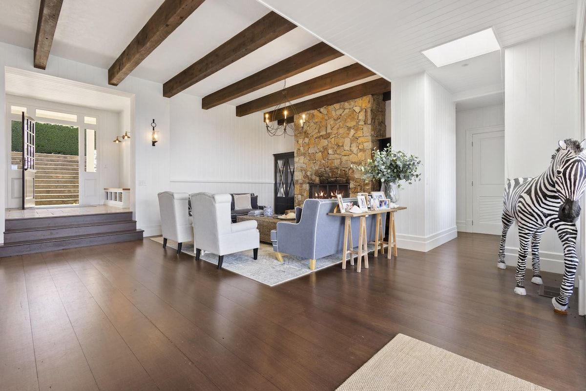 A spacious living room with a stone fireplace, a staircase, and a zebra statue.