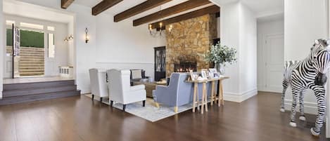 A spacious living room with a stone fireplace, a staircase, and a zebra statue.