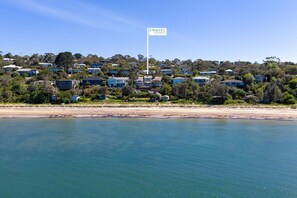 Un quartier résidentiel situé sur la côte, avec des maisons, un drapeau et une plage.