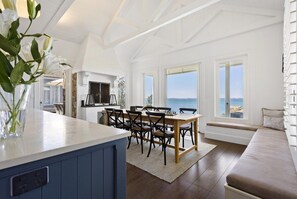 Une pièce spacieuse avec une grande table à manger, un banc intégré et une vue sur la mer.