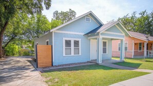 A two-story house with a front porch, a wooden fence, and a well-maintained lawn. - Nice, Cozy and Comfortable 3 BR Near Downtown (San Antonio)