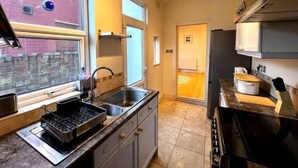 A modern kitchen with a built-in oven, a sink, and a window with decorative glass panels. - Birmingham Cottage Contractors Family SelfCheck in (West Midlands)