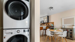 A laundry area with stacked washing machines and a modern kitchen with white cabinets, a dining table, and chairs. - Tropical Sunset Penthouse • Rooftop & Hot Tub (Cabo Rojo)