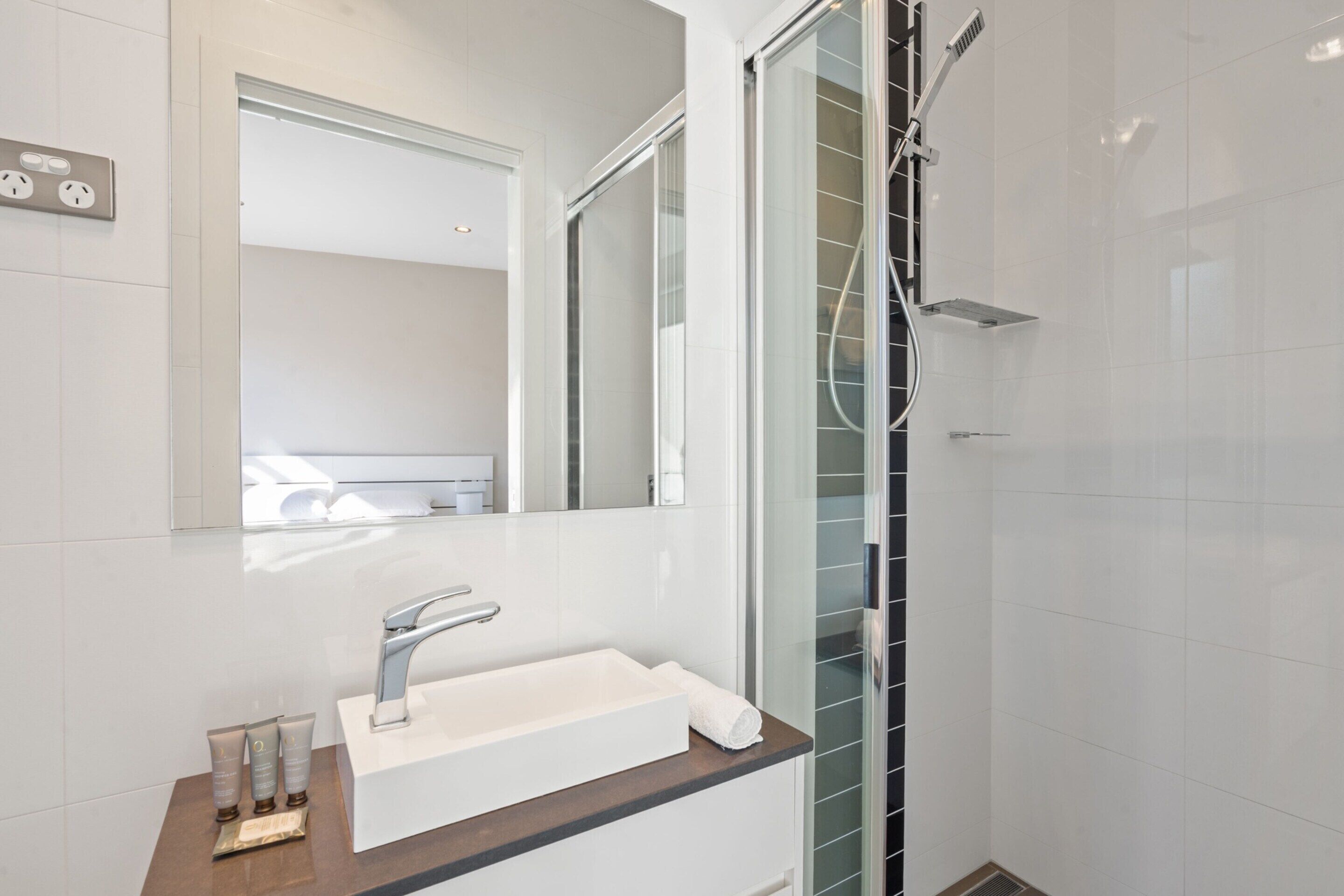 A modern bathroom with a white sink, a large mirror, and a glass shower enclosure.