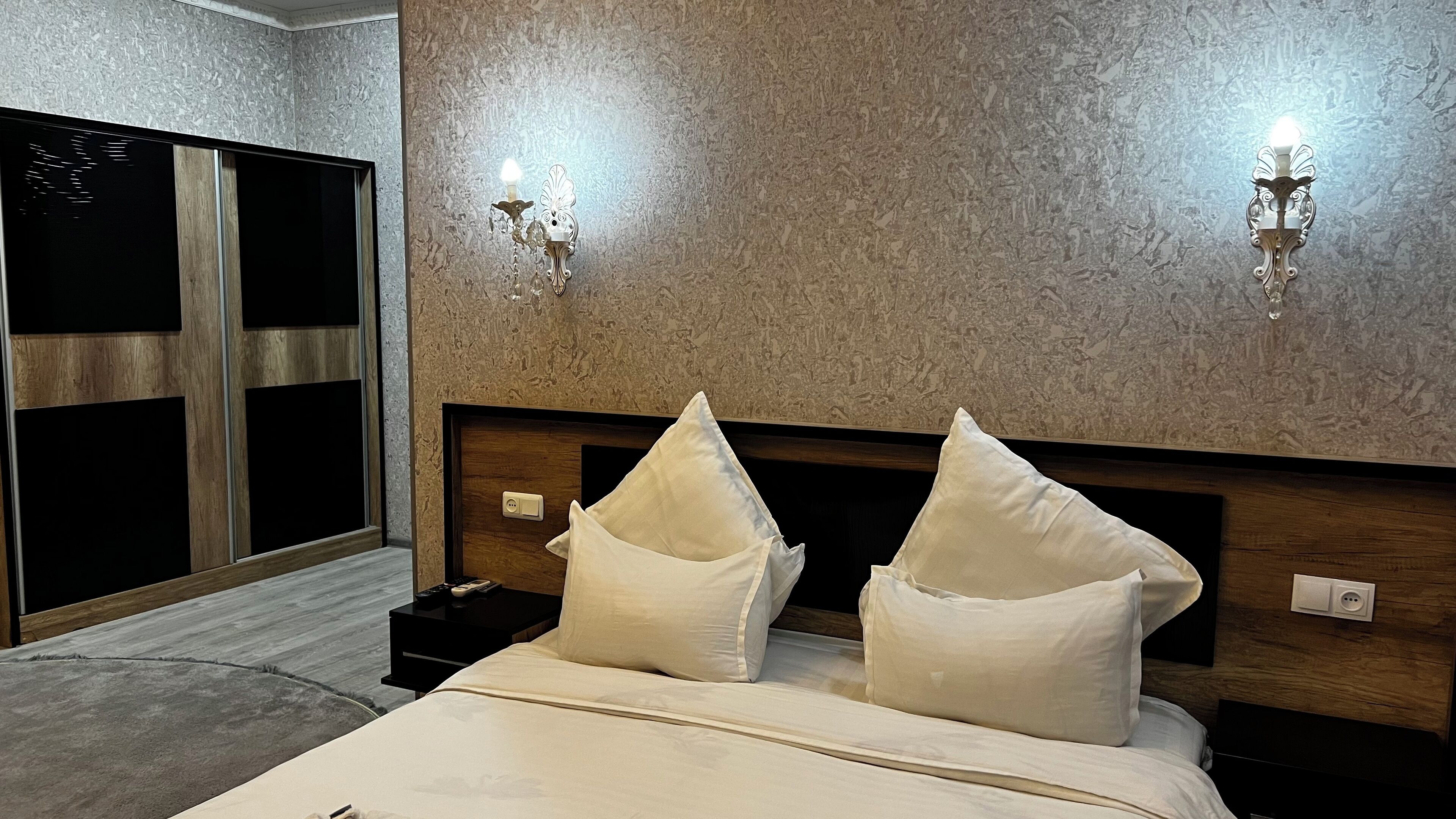 A modern hotel room with a wooden headboard, two bedside lamps, and a large bed with white bedding.