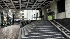 Una escalera conduce a un edificio con techo estampado y suelo de baldosas.