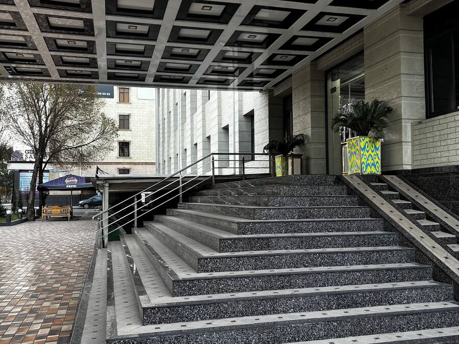 A staircase leading to a building with a patterned ceiling and a tiled floor.