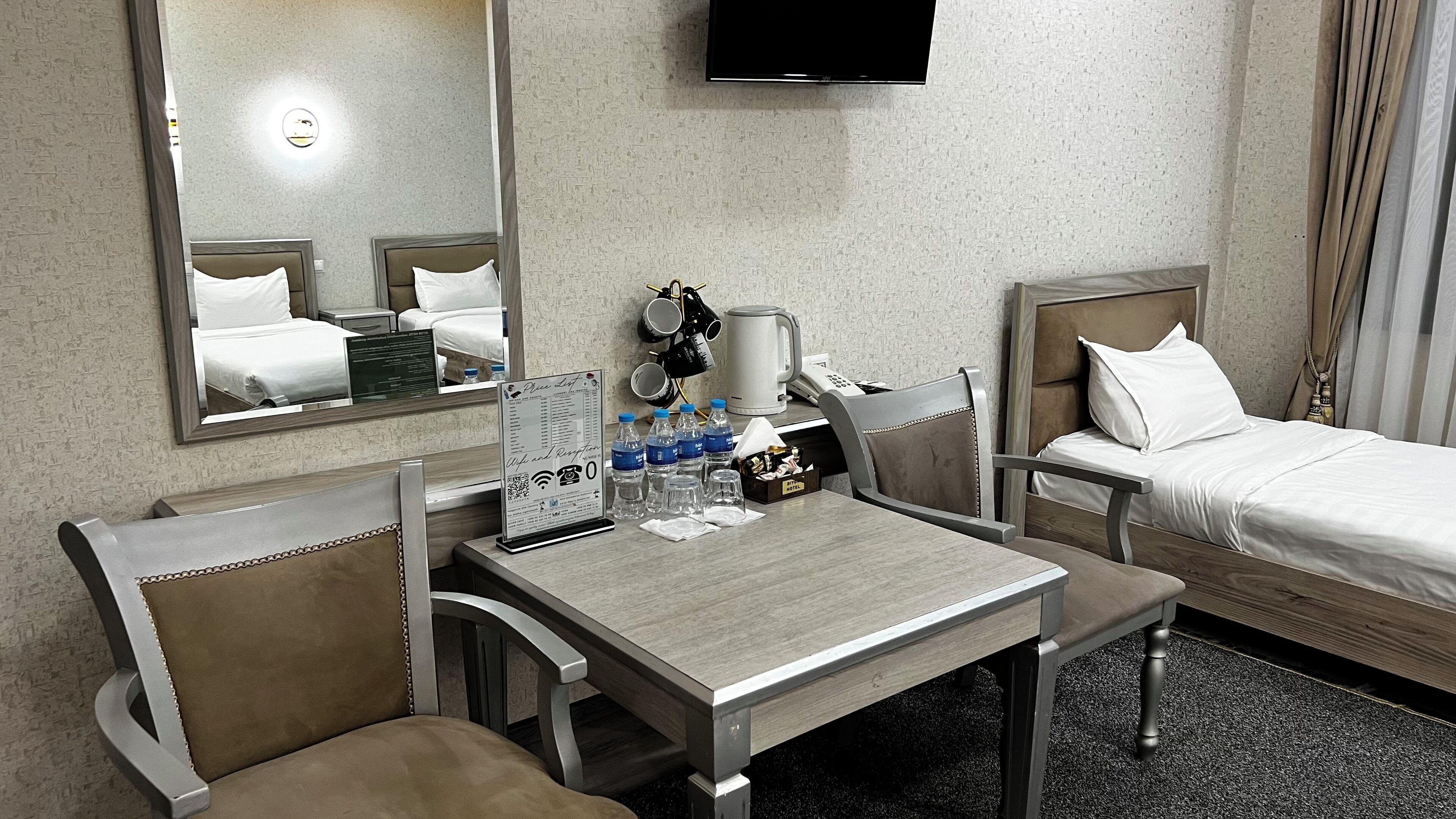 A hotel room with a bed, a desk, two chairs, a television, and a coffee maker.