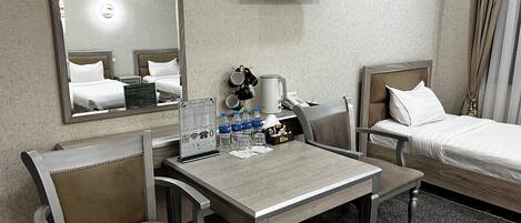 A hotel room with a bed, a desk, two chairs, a television, and a coffee maker.