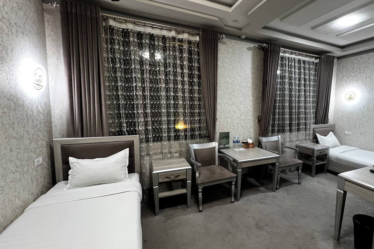 A hotel room with a bed, a desk, two chairs, a small table, and a nightstand.
