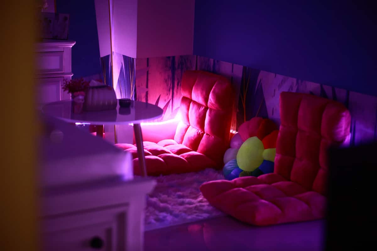 Una habitación con una butaca tapizada de rojo, una mesita redonda y un armario blanco.