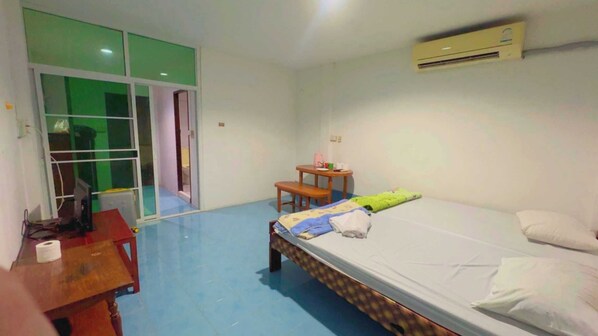 A room with a bed, a desk, a chair, a small table, and a window with green-tinted glass. - OYO 75596 The Sirisuk House (Si Samrong)