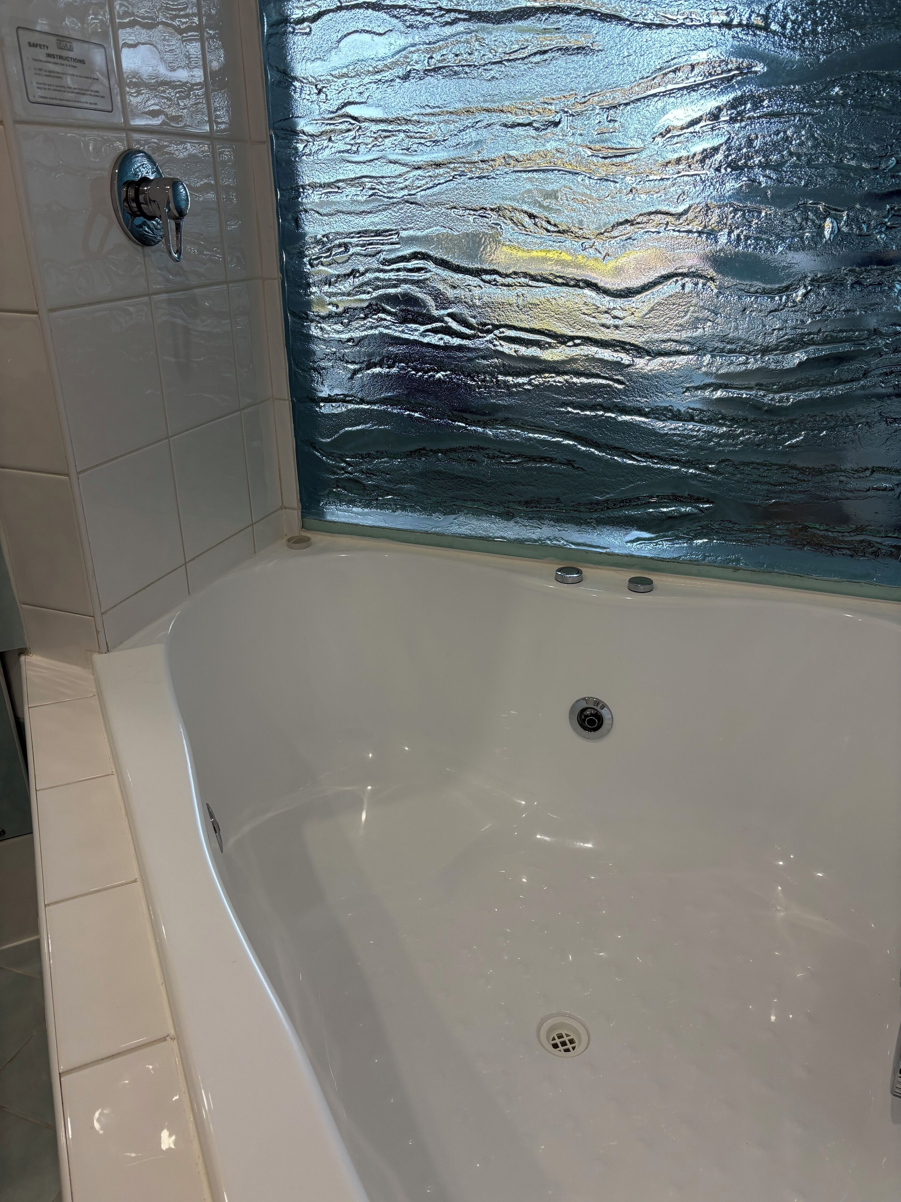 Una vasca da bagno con un muro in vetro.