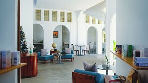 A spacious living area with a high ceiling, a ceiling fan, and a Christmas tree. There are several seating areas with sofas and chairs, and a dining table with chairs. - Serenity Home (Siem Reap)