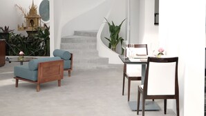 A modern interior with a spiral staircase, a dining area, and a decorative Buddha statue. - Serenity Home (Siem Reap)