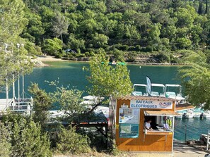 A wooden kiosk with a sign 'BATEAUX ELECTRIQUES' and a view of boats on water. - Charming two-bedroom apartment with a garden   (Saint-Julien)