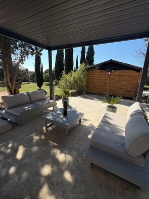 An outdoor patio with a covered seating area, a wooden fence, and a view of the surrounding landscape. - Charming two-bedroom apartment with a garden   (Saint-Julien)