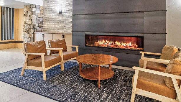 A modern living room with a fireplace, leather sofas, and a round coffee table. - Best in Breck. Ski in, ski out. Pool and hot tubs. (Breckenridge)