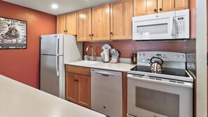 A compact kitchen with a refrigerator, microwave, stove, and dishwasher. - Best in Breck. Ski in, ski out. Pool and hot tubs. (Breckenridge)