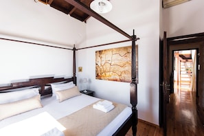 A four-poster bed with white linens, a bedside table with a lamp, and a large abstract painting on the wall. - Tzivaeri, Lovely village house with ample outdoor area and plunge pool. (Chania)