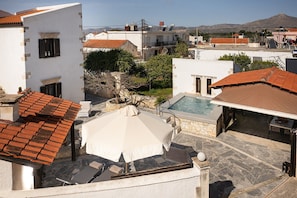 A rooftop pool area with a stone pool, lounge chairs, and a covered seating area. - Tzivaeri, Lovely village house with ample outdoor area and plunge pool. (Chania)