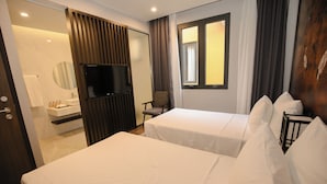 A hotel room with two beds, a TV, a chair, a window, and a bathroom visible through an open door. - Lynntimes Thanh Thuy Wellness Resort (Thanh Thuy)