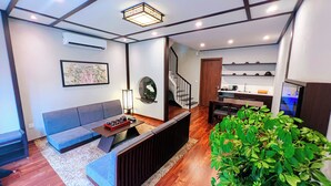 A modern living space with a sofa, coffee table, and a staircase leading to a kitchen area. - Lynntimes Thanh Thuy Wellness Resort (Thanh Thuy)