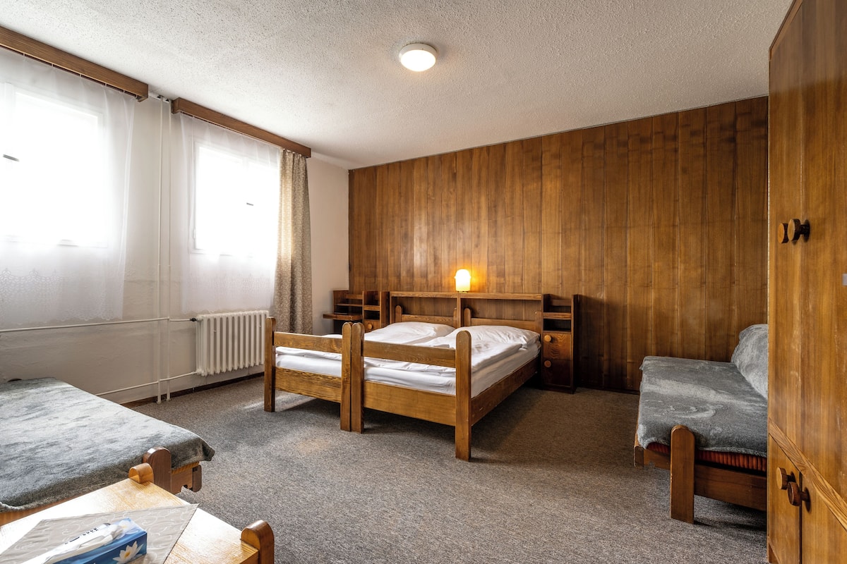 A room with two wooden beds, a wooden wardrobe, a small table, and a radiator.
