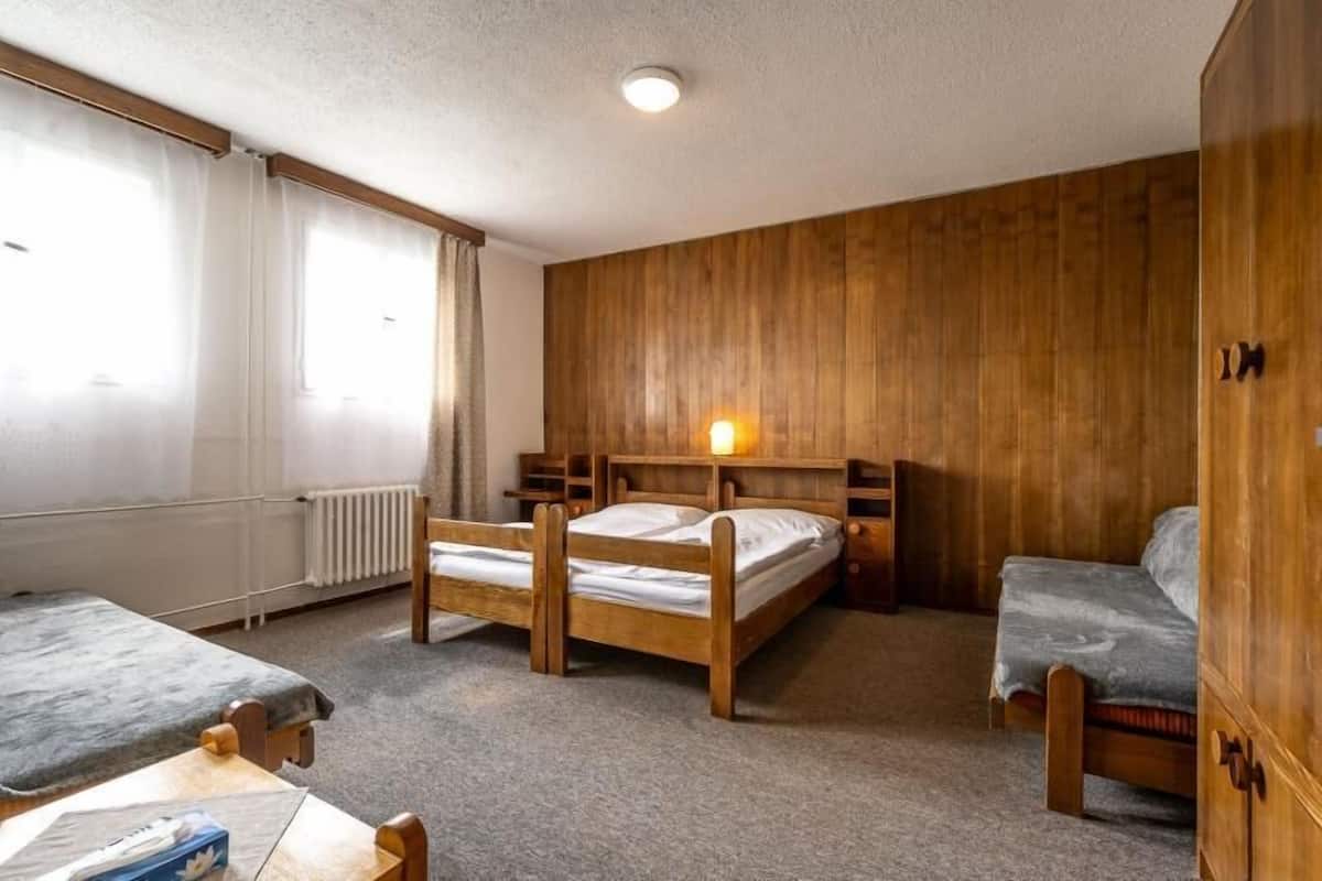 A room with two wooden bunk beds, a wooden wardrobe, and a table with a box on it.