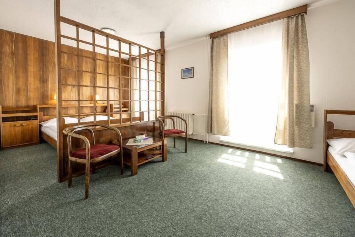 A room with a bunk bed, a wooden desk, a chair, and a radiator.