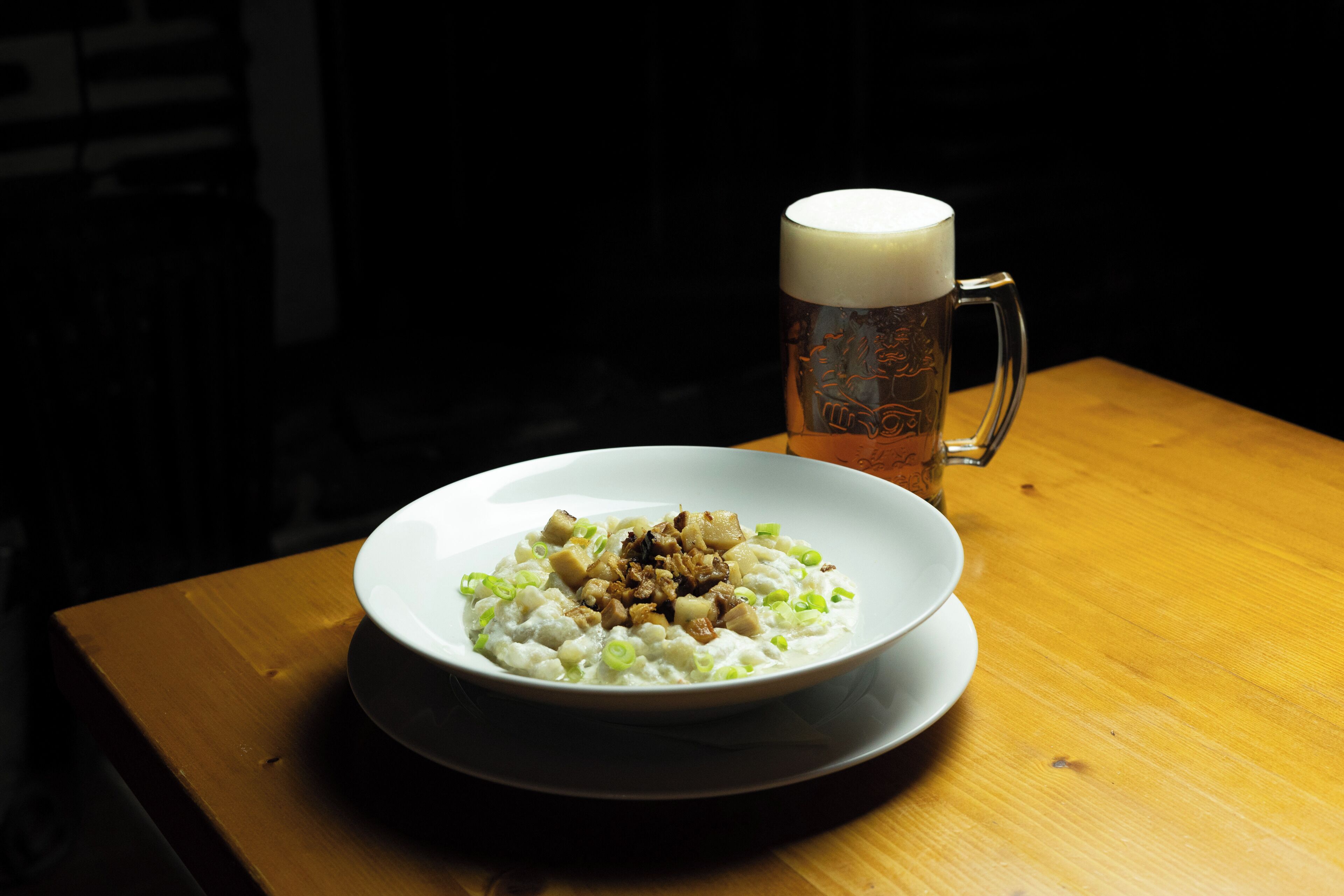 A plate of food with a mug of beer on a wooden table.