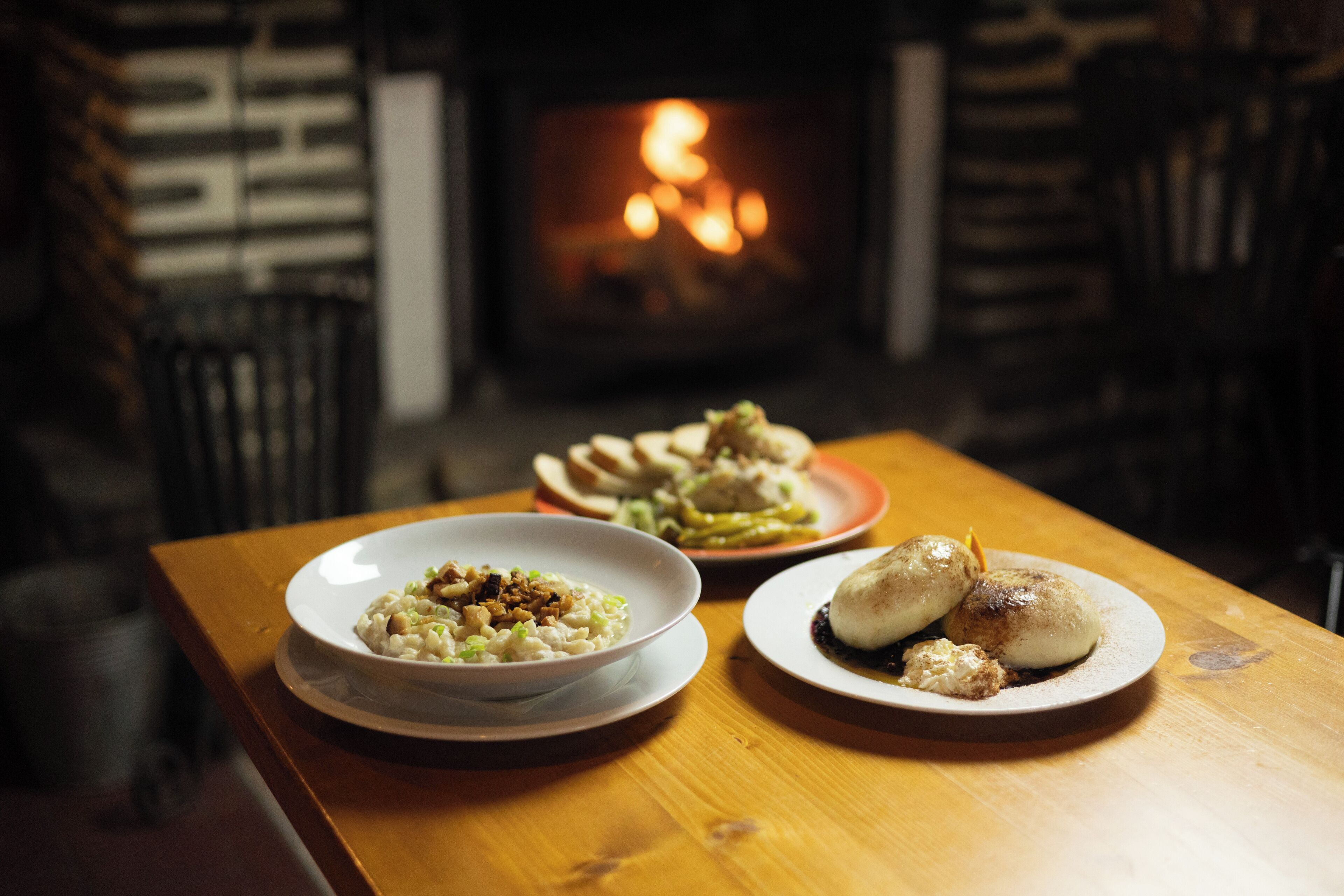 A table with plates of food and a fireplace in the background.