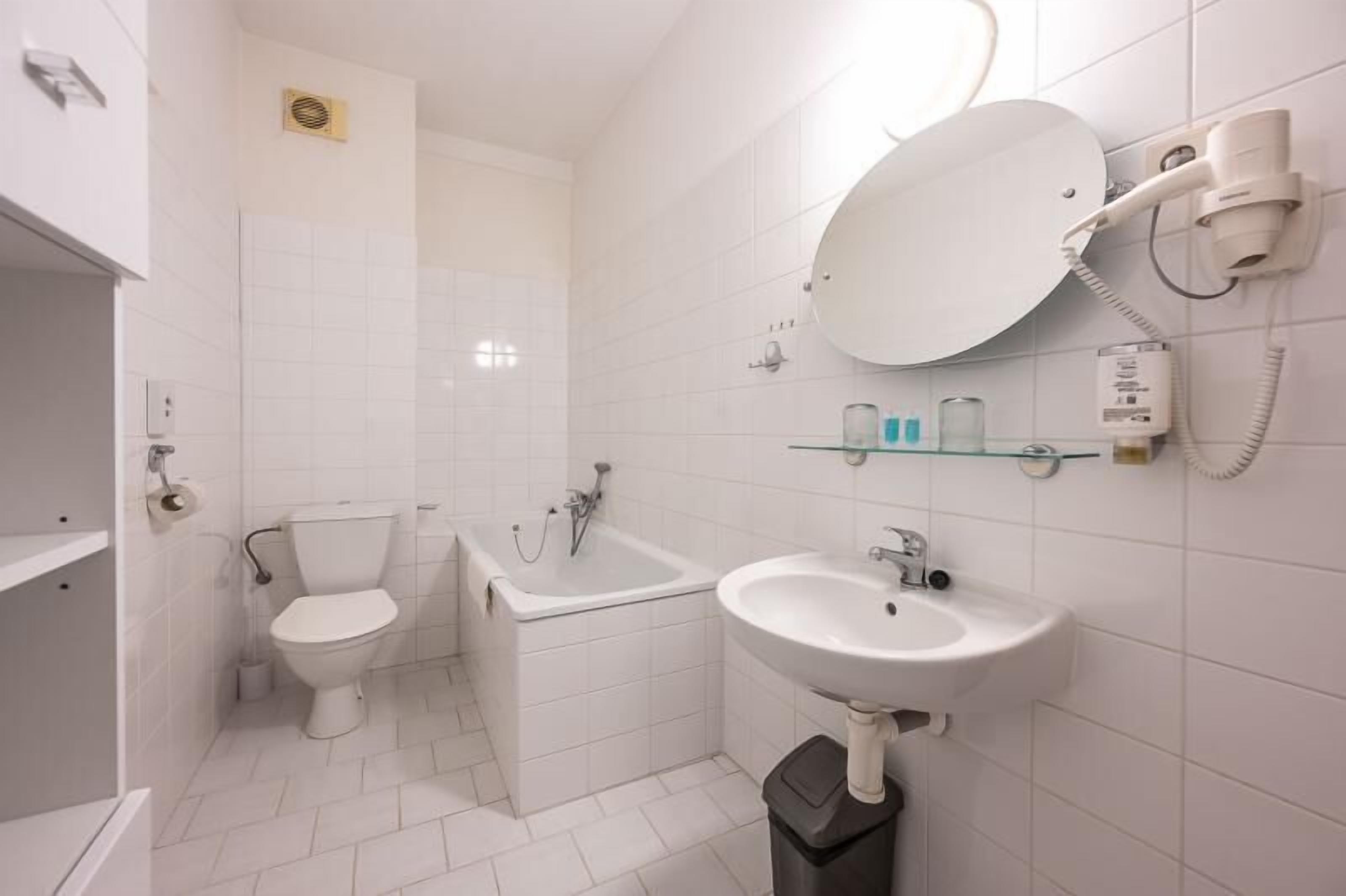Une salle de bain moderne équipée de toilettes, d’une baignoire et d’un lavabo.