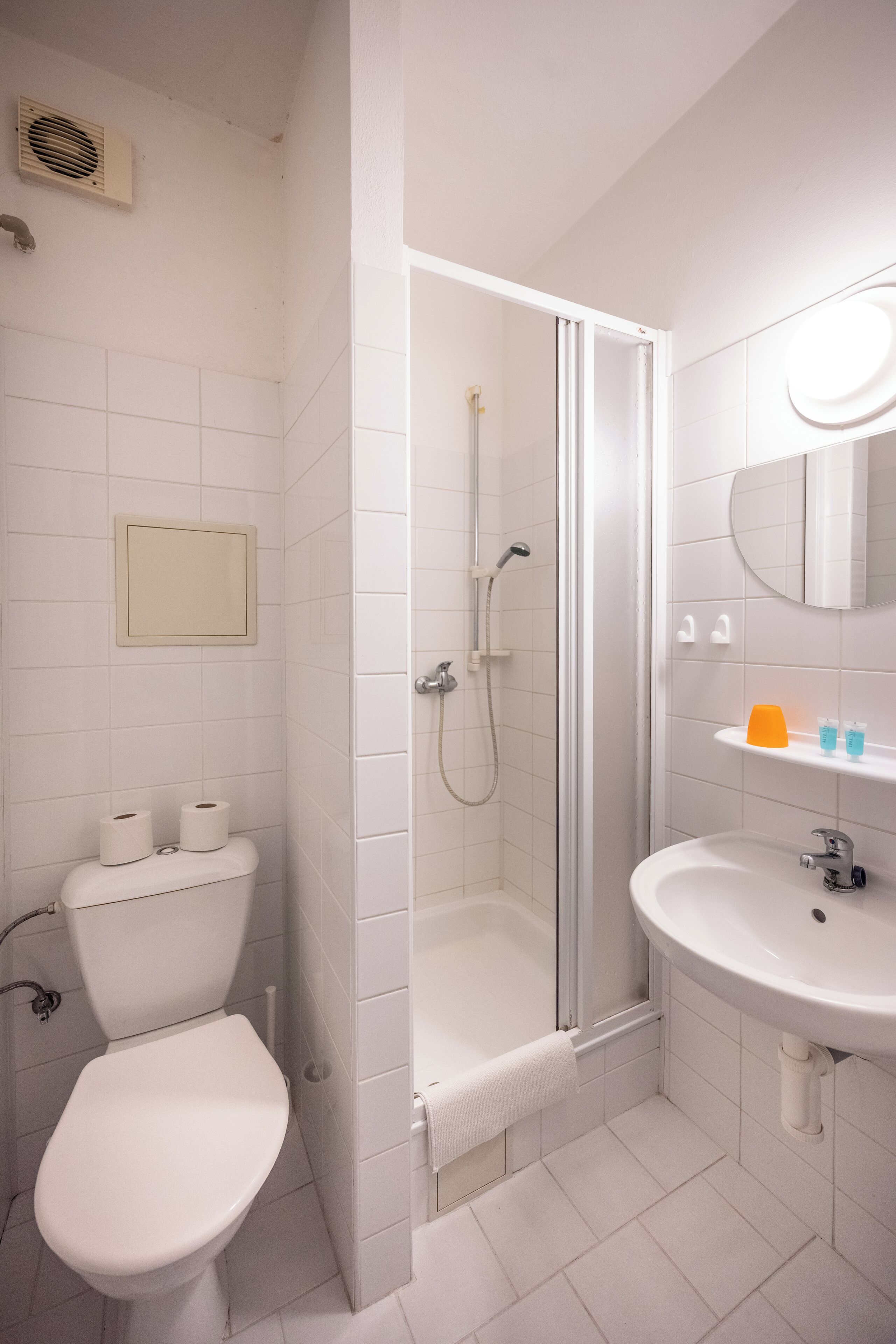 A bathroom with a toilet, a shower, and a sink.