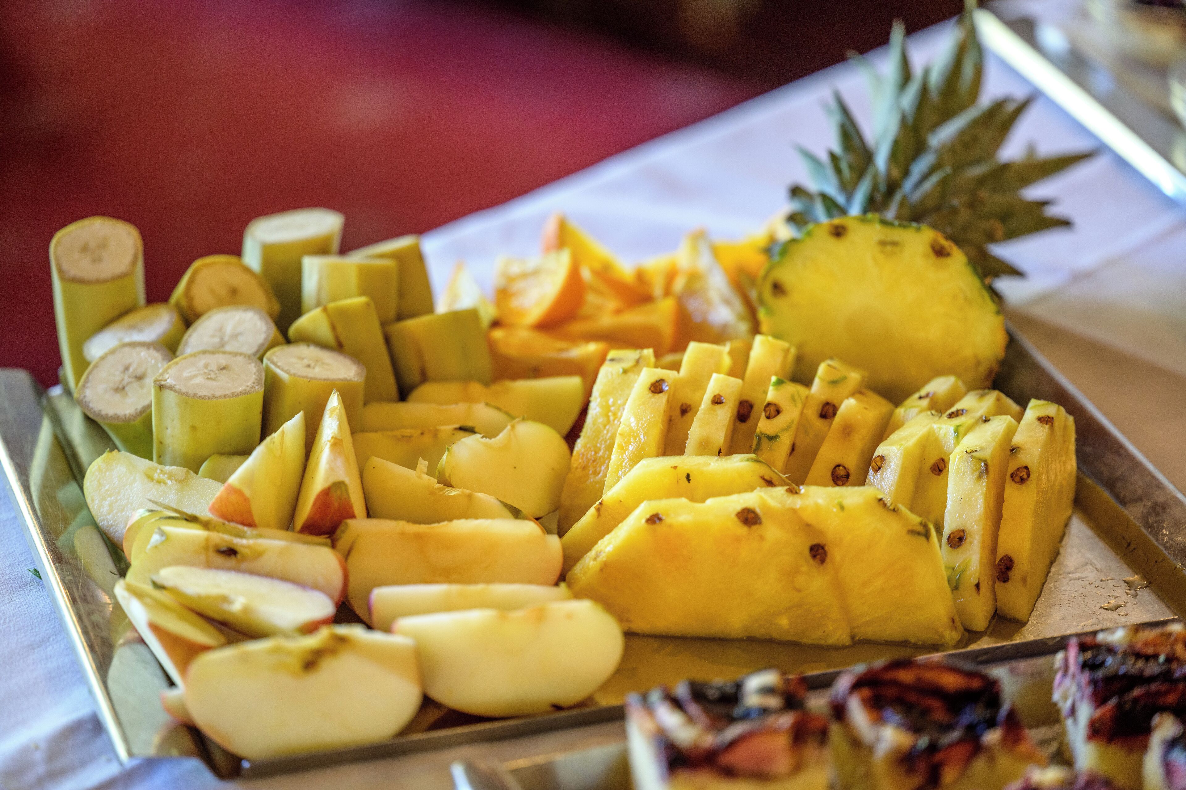 Een schaal met plakken fruit, zoals bananen, appels en ananas.