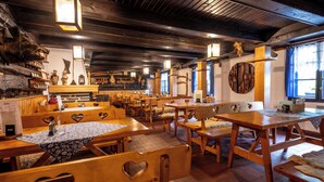 A rustic wooden interior with benches and tables, wooden beams on the ceiling, and decorative wall items. - Hotel Tanečnica (Prostredni Becva)
