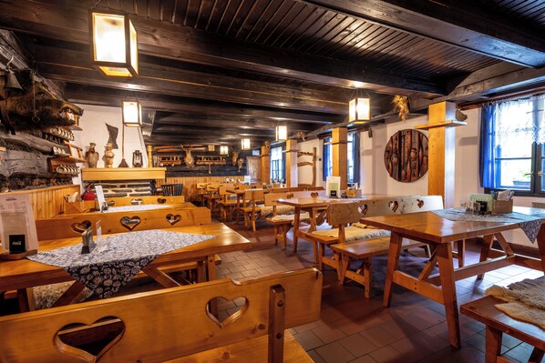 A rustic wooden interior with benches and tables, wooden beams on the ceiling, and decorative wall items. - Hotel Tanečnica (Prostredni Becva)