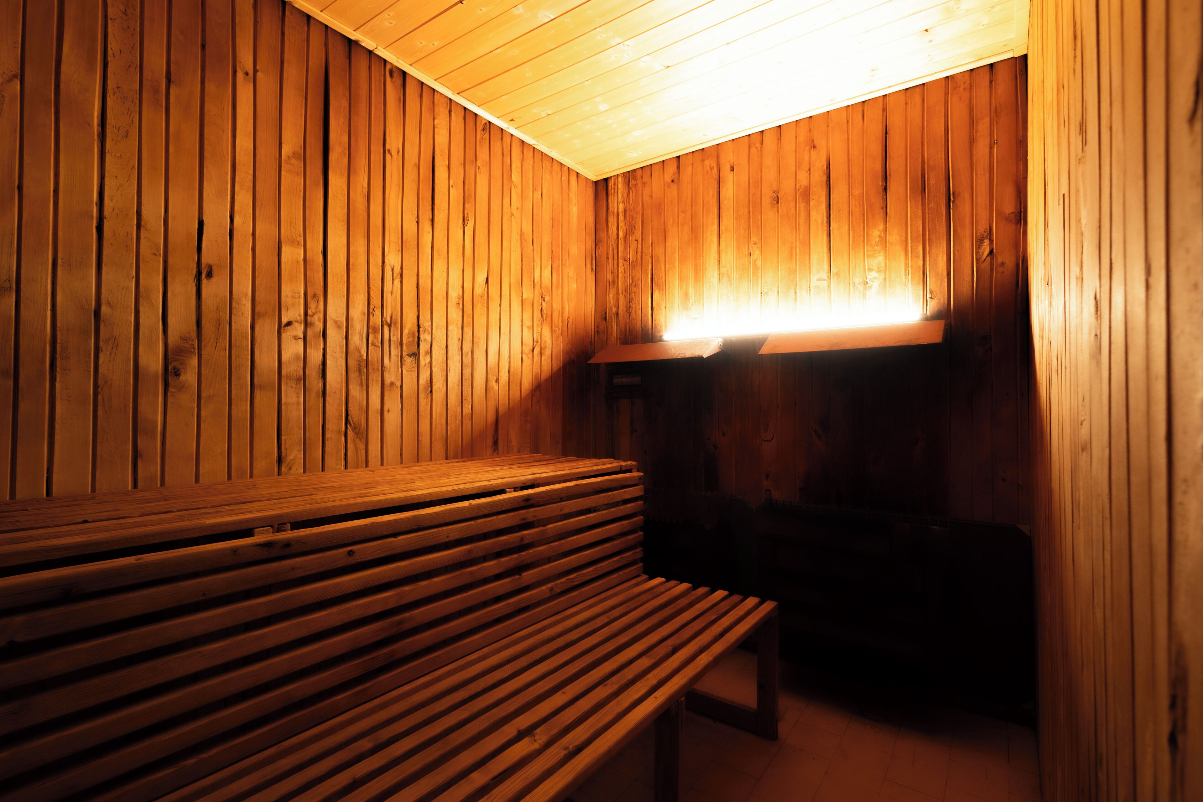 Eine Holzsauna mit Bänken, im Vordergrund eine Sitzbank.